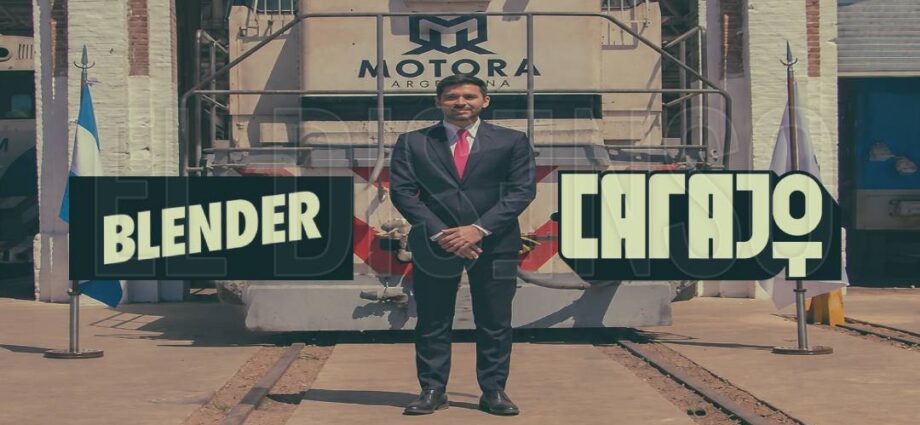 El empresario Augusto Marini junto a una locomotora con el logo de Motora Argentina y los logotipos de los canales de streaming Carajo y Blender.